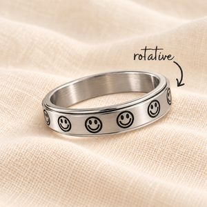 Bague Sourire argentée à motifs noirs sur lin crème avec flèche rotative